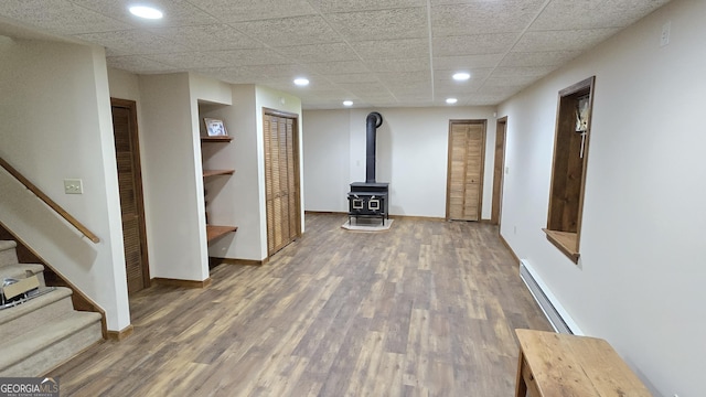 396 Greenleaf Dr, Lavonia, GA 30553 - below grade area with baseboard heating, a wood stove, wood finished floors, stairway, and recessed lighting