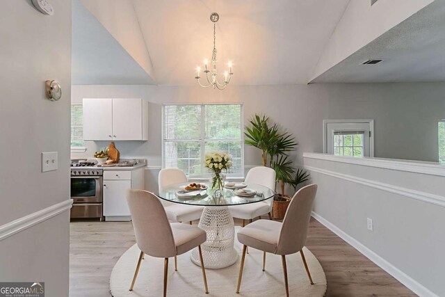 5421 Salem Springs Dr, Lithonia, GA 30038 - dining area featuring a chandelier, light wood-style flooring, and high vaulted ceiling