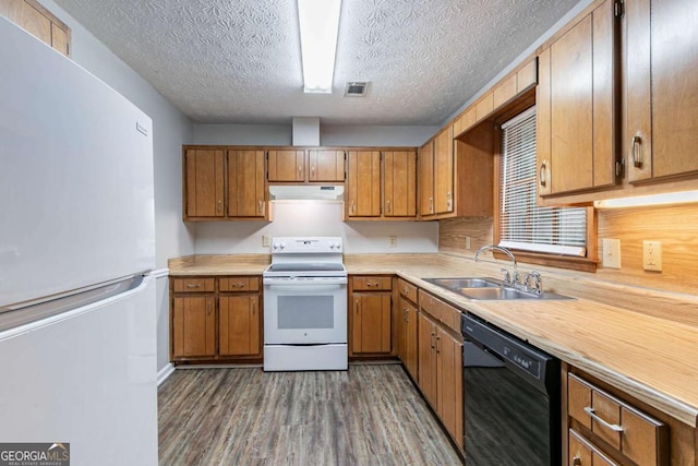 604 Hamlet Ct SE, Conyers, GA 30094 - kitchen featuring white appliances, under cabinet range hood, a sink, dark wood finished floors, and brown cabinets