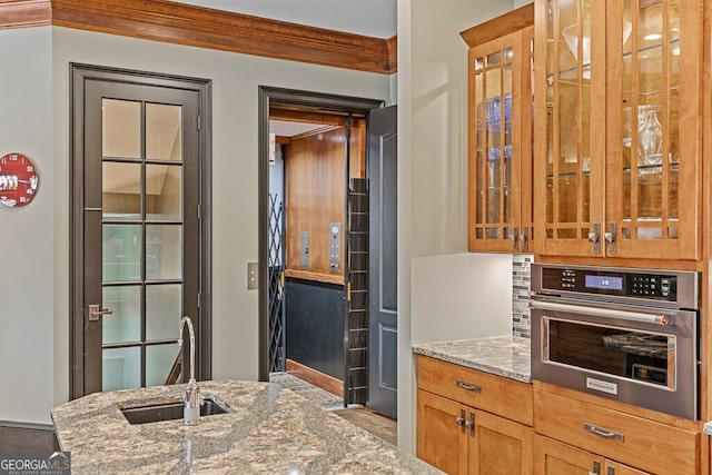 2304 Weeping Oak Dr, Braselton, GA 30517 - kitchen featuring stainless steel oven, a sink, light stone counters, and glass insert cabinets