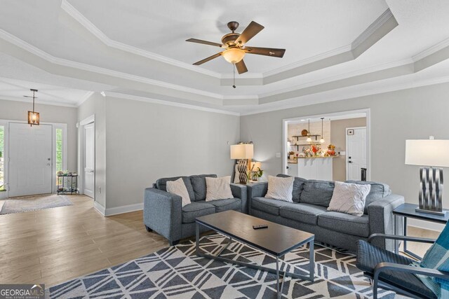 344 Mckibben Dr, Locust Grove, GA 30248 - living area with a tray ceiling, ceiling fan, light wood-type flooring, baseboards, and crown molding