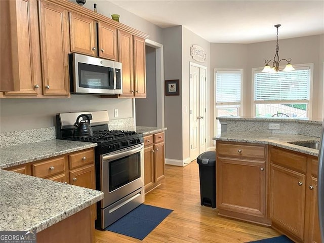107 Sedgefield Overlook, Dallas, GA 30157 - kitchen with stainless steel appliances, brown cabinets, light wood-style floors, and light stone counters