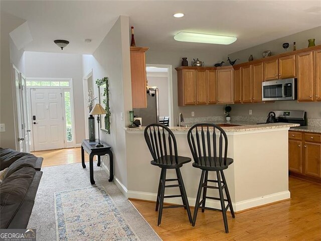 107 Sedgefield Overlook, Dallas, GA 30157 - kitchen with stainless steel appliances, a breakfast bar, a peninsula, light wood finished floors, and open floor plan