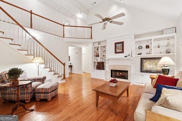 2722 Brookhaven Ln, Buford, GA 30518 - living area with light wood finished floors, a ceiling fan, stairs, a fireplace with flush hearth, and high vaulted ceiling