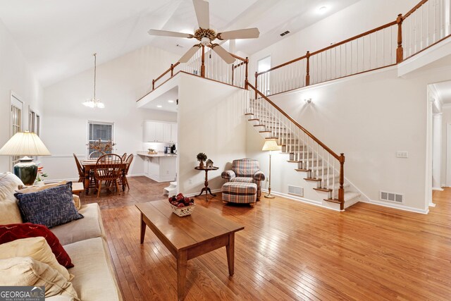 2722 Brookhaven Ln, Buford, GA 30518 - living room with high vaulted ceiling, hardwood / wood-style floors, a ceiling fan, stairs, and a chandelier