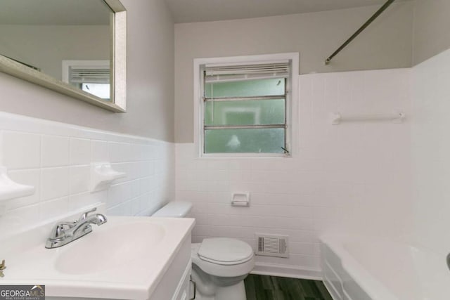 2582 Springdale Rd SW, Atlanta, GA 30315 - bathroom with tile walls, toilet, vanity, wood finished floors, and tub / shower combination