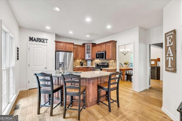 1637 Willow Way, Woodstock, GA 30188 - kitchen featuring stainless steel appliances, brown cabinets, a kitchen bar, decorative backsplash, and light stone countertops