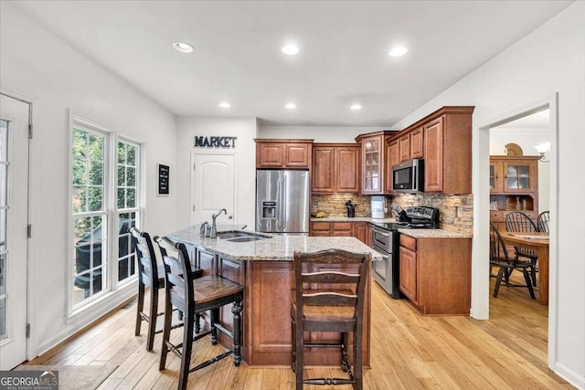 1637 Willow Way, Woodstock, GA 30188 - kitchen featuring stainless steel appliances, a sink, light wood-style flooring, brown cabinetry, and backsplash