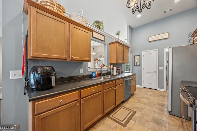 5511 Preserve Pt, Flowery Branch, GA 30542 - kitchen featuring appliances with stainless steel finishes, dark countertops, brown cabinets, a towering ceiling, and a chandelier