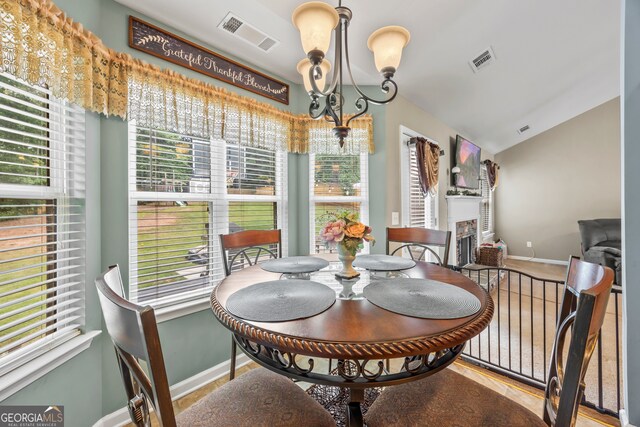 5511 Preserve Pt, Flowery Branch, GA 30542 - dining space featuring a chandelier, plenty of natural light, vaulted ceiling, and a fireplace