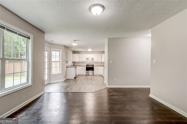 7006 Mahonia Pl, Lithonia, GA 30038 - unfurnished living room featuring a textured ceiling, dark wood-type flooring, baseboards, and a sink