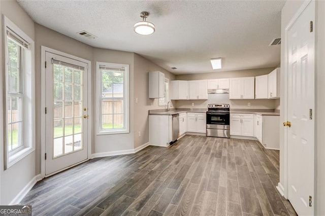 7006 Mahonia Pl, Lithonia, GA 30038 - kitchen with stainless steel appliances, dark wood-type flooring, baseboards, a textured ceiling, and white cabinets