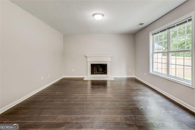 7006 Mahonia Pl, Lithonia, GA 30038 - unfurnished living room featuring dark wood-style floors, a fireplace with raised hearth, a textured ceiling, and baseboards
