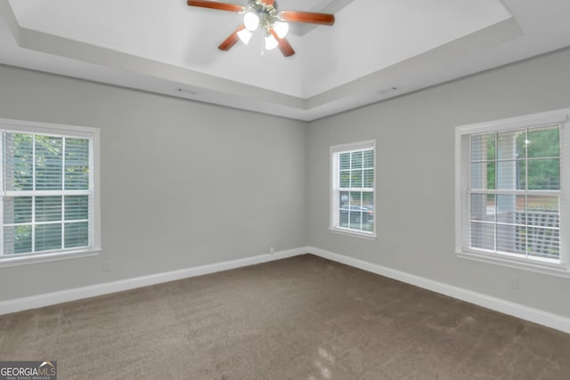 185 Stewart Glen Dr, Covington, GA 30014 - empty room with a raised ceiling, dark carpet, ceiling fan, and baseboards