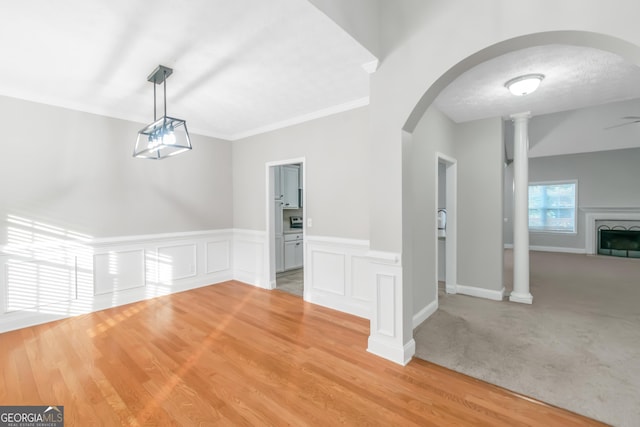 185 Stewart Glen Dr, Covington, GA 30014 - unfurnished dining area featuring arched walkways, a fireplace, wainscoting, light wood finished floors, and decorative columns