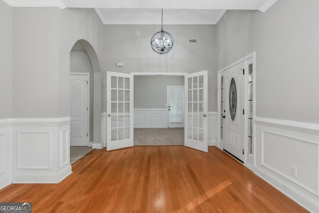 185 Stewart Glen Dr, Covington, GA 30014 - foyer entrance featuring french doors, a decorative wall, light wood-style flooring, a chandelier, and wainscoting