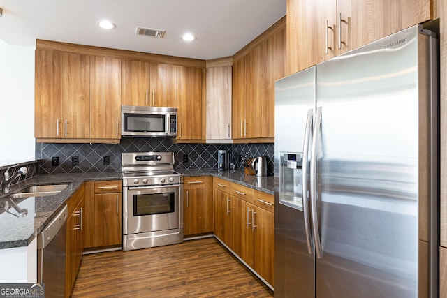 1080 Peachtree St NE Unit 2116, Atlanta, GA 30309 - kitchen featuring stainless steel appliances, brown cabinets, dark stone countertops, dark wood-type flooring, and recessed lighting