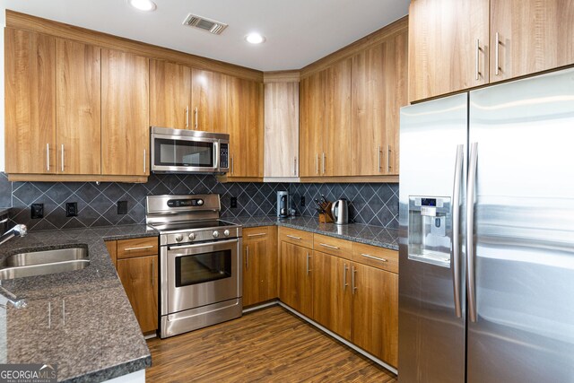 1080 Peachtree St NE Unit 2116, Atlanta, GA 30309 - kitchen with appliances with stainless steel finishes, dark wood-style floors, decorative backsplash, brown cabinets, and recessed lighting