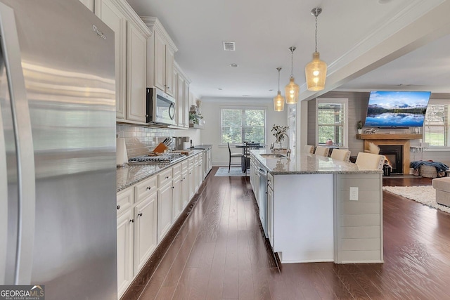406 Fernstone Dr, Canton, GA 30114 - kitchen featuring appliances with stainless steel finishes, a sink, open floor plan, light stone countertops, and a fireplace