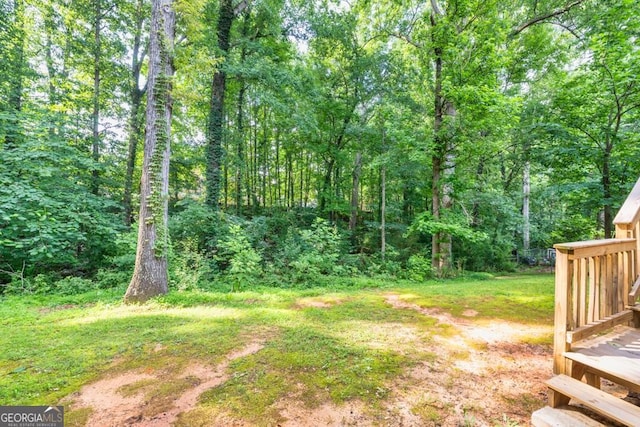 241 Tweed Ct, Sugar Hill, GA 30518 - view of yard with a forest view and a wooden deck