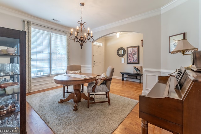 300 Brackin Trce, Grayson, GA 30017 - dining area featuring arched walkways, ornamental molding, light wood-style flooring, a wainscoted wall, and a chandelier