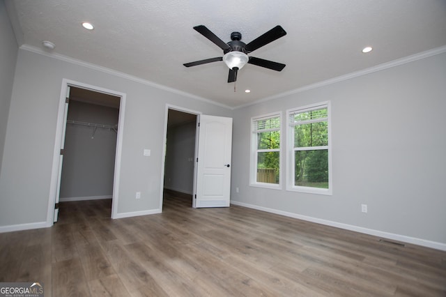 74 Preacher Smith Rd SE, Silver Creek, GA 30173 - unfurnished bedroom with a walk in closet, wood finished floors, baseboards, crown molding, and recessed lighting