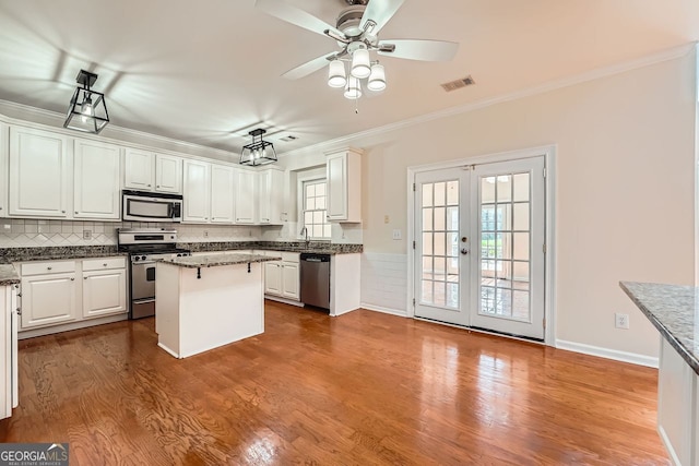 1713 Paramore Pl NE, Marietta, GA 30062 - kitchen with appliances with stainless steel finishes, ornamental molding, white cabinetry, a kitchen island, and dark wood-style floors