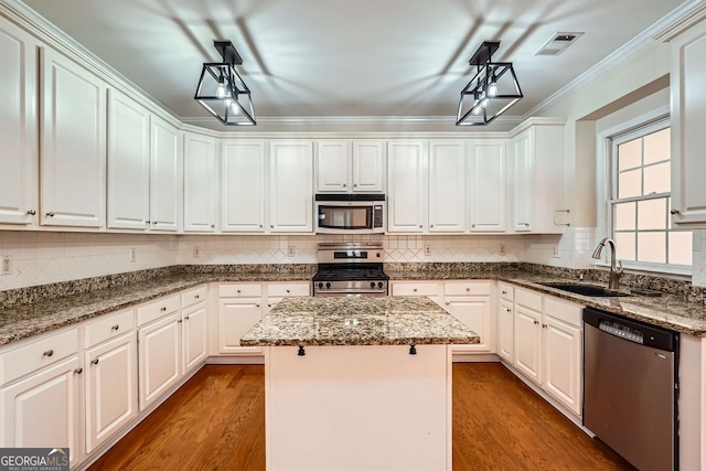 1713 Paramore Pl NE, Marietta, GA 30062 - kitchen with appliances with stainless steel finishes, a kitchen island, white cabinetry, wood finished floors, and crown molding