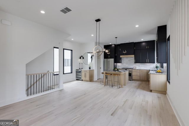 1962 8th St, Chamblee, GA 30341 - kitchen featuring appliances with stainless steel finishes, beverage cooler, dark cabinets, open floor plan, and light wood-style flooring