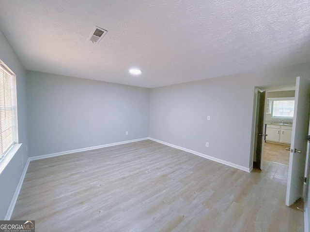 1820 Neely Ave, Atlanta, GA 30344 - spare room featuring light wood-style flooring, healthy amount of natural light, a textured ceiling, baseboards, and a sink