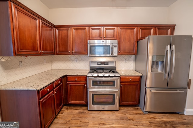 4135 Arch Pass, Cumming, GA 30040 - kitchen with appliances with stainless steel finishes, light stone counters, backsplash, and wood finished floors
