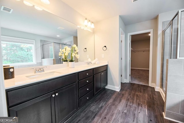 3557 Bryant Meadows Cir, Buford, GA 30519 - bathroom featuring a shower stall, double vanity, a walk in closet, and wood finished floors