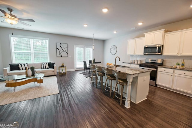 3557 Bryant Meadows Cir, Buford, GA 30519 - kitchen featuring stainless steel appliances, tasteful backsplash, a kitchen island with sink, a breakfast bar, and light stone countertops