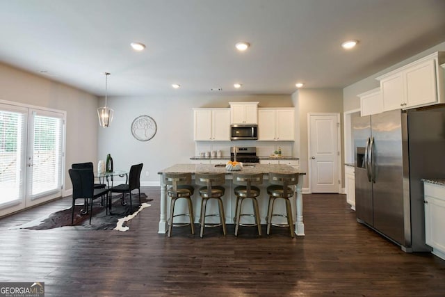 3557 Bryant Meadows Cir, Buford, GA 30519 - kitchen featuring appliances with stainless steel finishes, dark wood finished floors, light stone counters, white cabinets, and a breakfast bar area