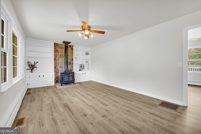 234 Edgewood Dr, Mount Airy, GA 30563 - unfurnished living room featuring a wood stove, wood finished floors, a ceiling fan, built in shelves, and baseboards