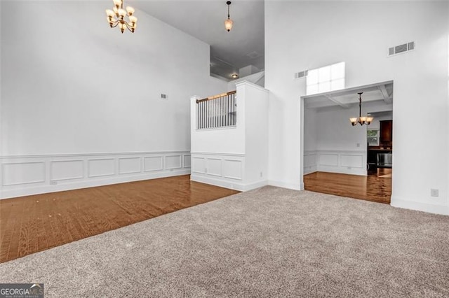 7601 Watson Cir, Locust Grove, GA 30248 - carpeted spare room featuring a chandelier, a towering ceiling, a decorative wall, and wainscoting