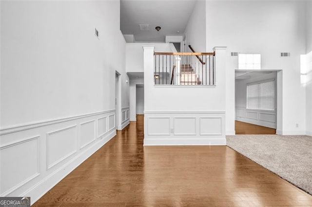 7601 Watson Cir, Locust Grove, GA 30248 - unfurnished living room featuring a high ceiling, a decorative wall, wood finished floors, and wainscoting
