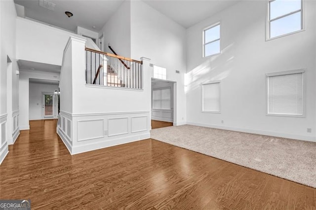 7601 Watson Cir, Locust Grove, GA 30248 - unfurnished living room with a towering ceiling, wood finished floors, and wainscoting