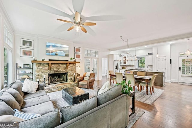 81 Cane Mill Ln, Dahlonega, GA 30533 - living area featuring a ceiling fan, a stone fireplace, a chandelier, crown molding, and light wood-style floors