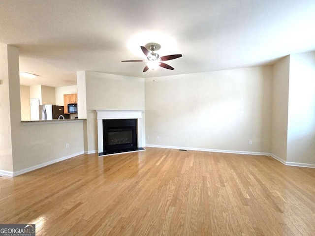 2104 Meadow Peak Rd, Duluth, GA 30097 - unfurnished living room featuring light wood-style floors, ceiling fan, and a glass covered fireplace