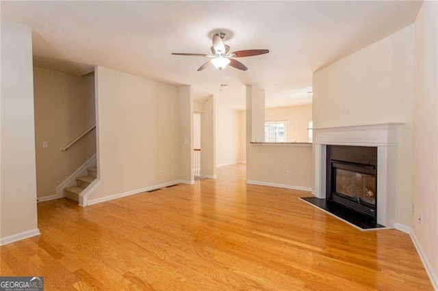 2104 Meadow Peak Rd, Duluth, GA 30097 - unfurnished living room with light wood-style floors, a ceiling fan, stairway, and a fireplace with flush hearth