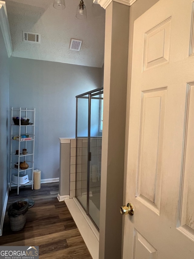 740 Pebble Blvd, Covington, GA 30016 - bathroom with wood finished floors, vaulted ceiling, a stall shower, baseboards, and a textured ceiling