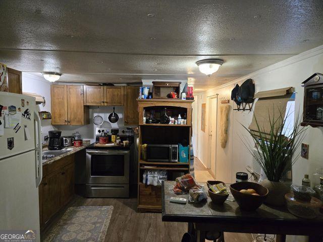 81 Shrader Ln, Ringgold, GA 30736 - kitchen featuring stainless steel appliances, brown cabinets, wood finished floors, a textured ceiling, and crown molding