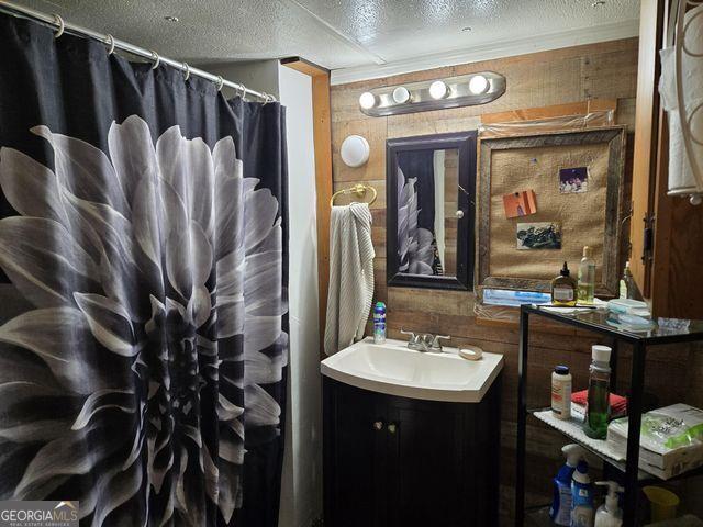 81 Shrader Ln, Ringgold, GA 30736 - full bathroom with a textured ceiling, wooden walls, vanity, and a shower with shower curtain