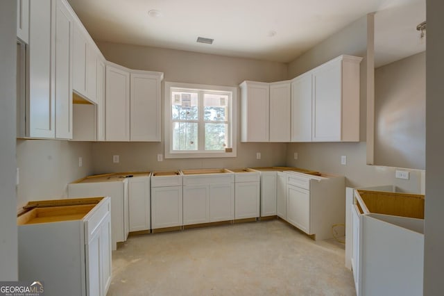 124 Flamingo Dr, Monticello, GA 31064 - kitchen with concrete floors and white cabinetry
