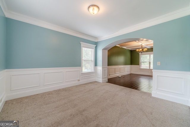 1022 Nestling Dr, Lawrenceville, GA 30045 - carpeted empty room with a chandelier, crown molding, a wainscoted wall, arched walkways, and a decorative wall