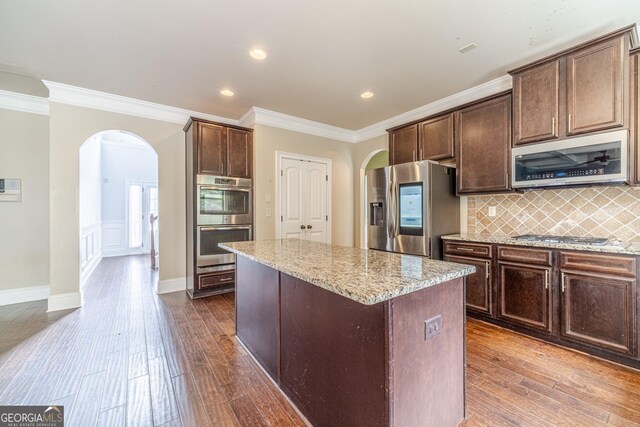 1022 Nestling Dr, Lawrenceville, GA 30045 - kitchen with arched walkways, appliances with stainless steel finishes, dark wood-style floors, crown molding, and light stone countertops