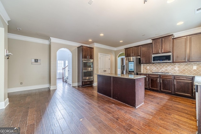 1022 Nestling Dr, Lawrenceville, GA 30045 - kitchen featuring arched walkways, stainless steel appliances, baseboards, tasteful backsplash, and a kitchen island