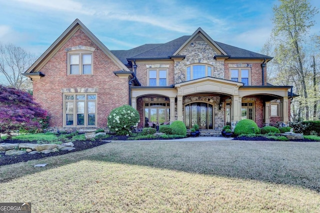 2279 Weeping Oak Dr, Braselton, GA 30517 - craftsman house featuring a front yard, brick siding, a porch, stone siding, and french doors