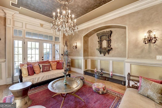 2279 Weeping Oak Dr, Braselton, GA 30517 - living room with french doors, wood finished floors, a chandelier, crown molding, and arched walkways